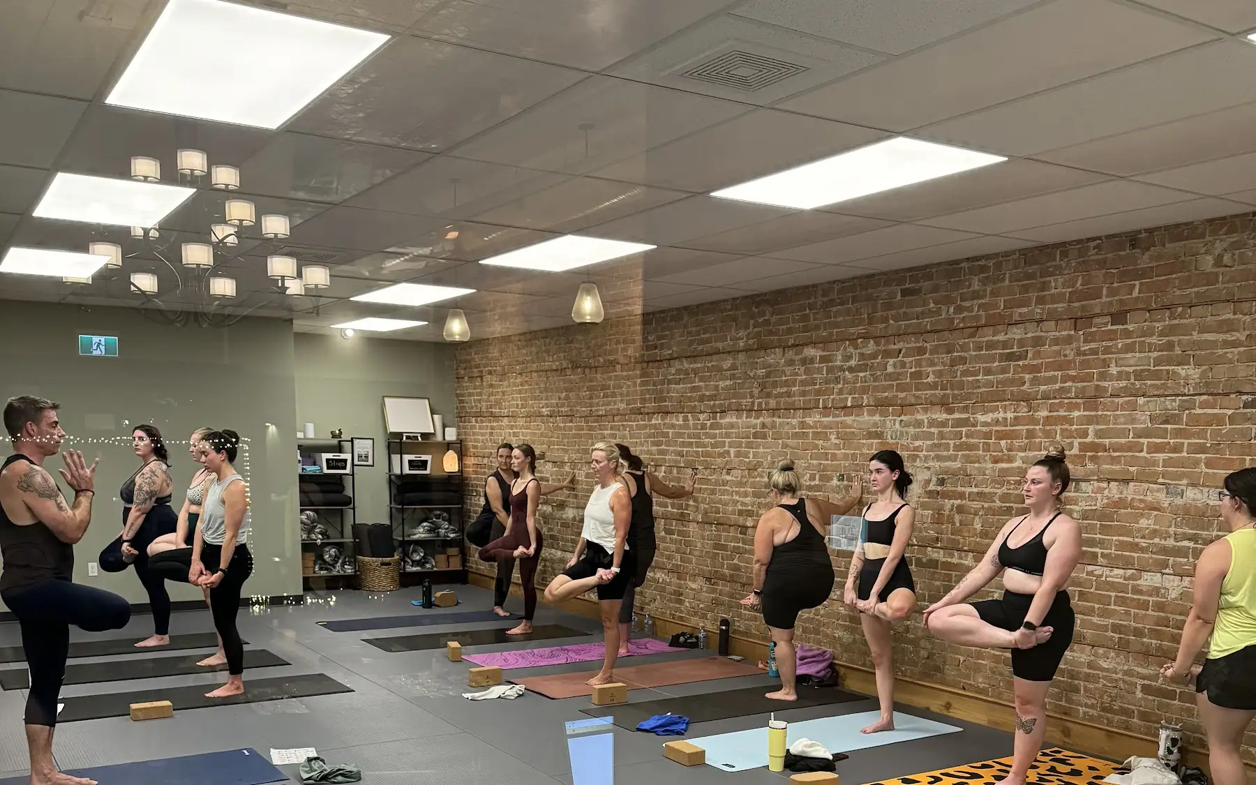 A full class balancing in tree pose in the practice room